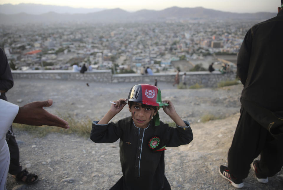 A boy poses with a hat which depicts the Afghan flag on Independence Day, in Kabul, Afghanistan, Monday, Aug. 19, 2019. Afghanistan's president is vowing to eliminate all safe havens of the Islamic State group as the country marks a subdued 100th Independence Day after a horrific wedding attack claimed by the local IS affiliate. (AP Photo/Rafiq Maqbool)