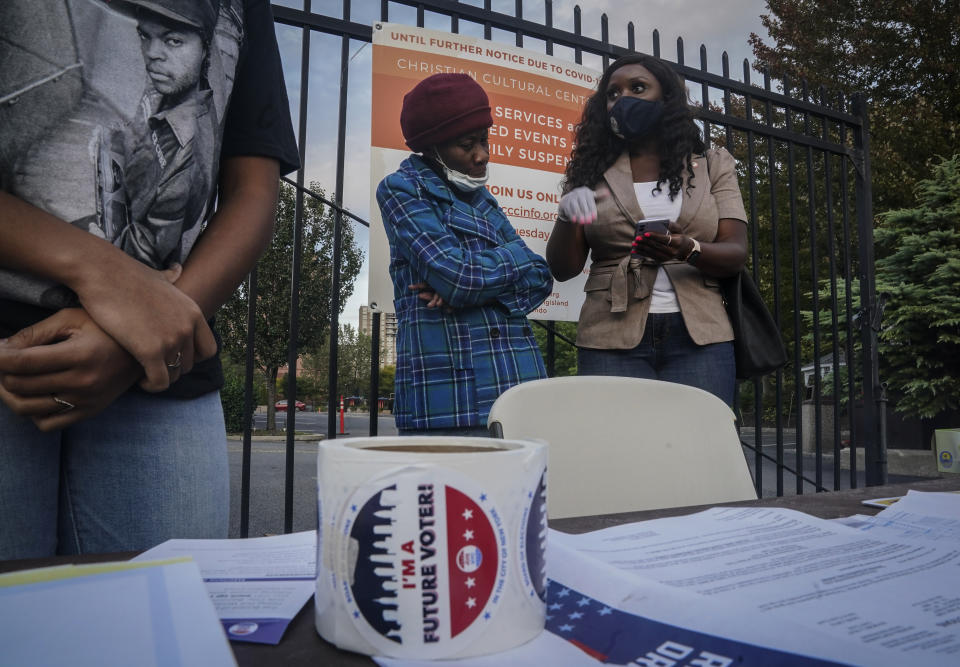 New York City Council member Farah Louis, right, who works as a volunteer with Christian Cultural Center's Social Justice Initiative's voter registration drive, tries to convince a woman to register at a table outside the the church, Thursday, Oct. 1, 2020, in the Brooklyn borough of New York. "Just a conversation of why it's important to vote will lead them to the polls," Louis said. "Souls to the polls campaign is about getting everyone to the polls." (AP Photo/Bebeto Matthews)