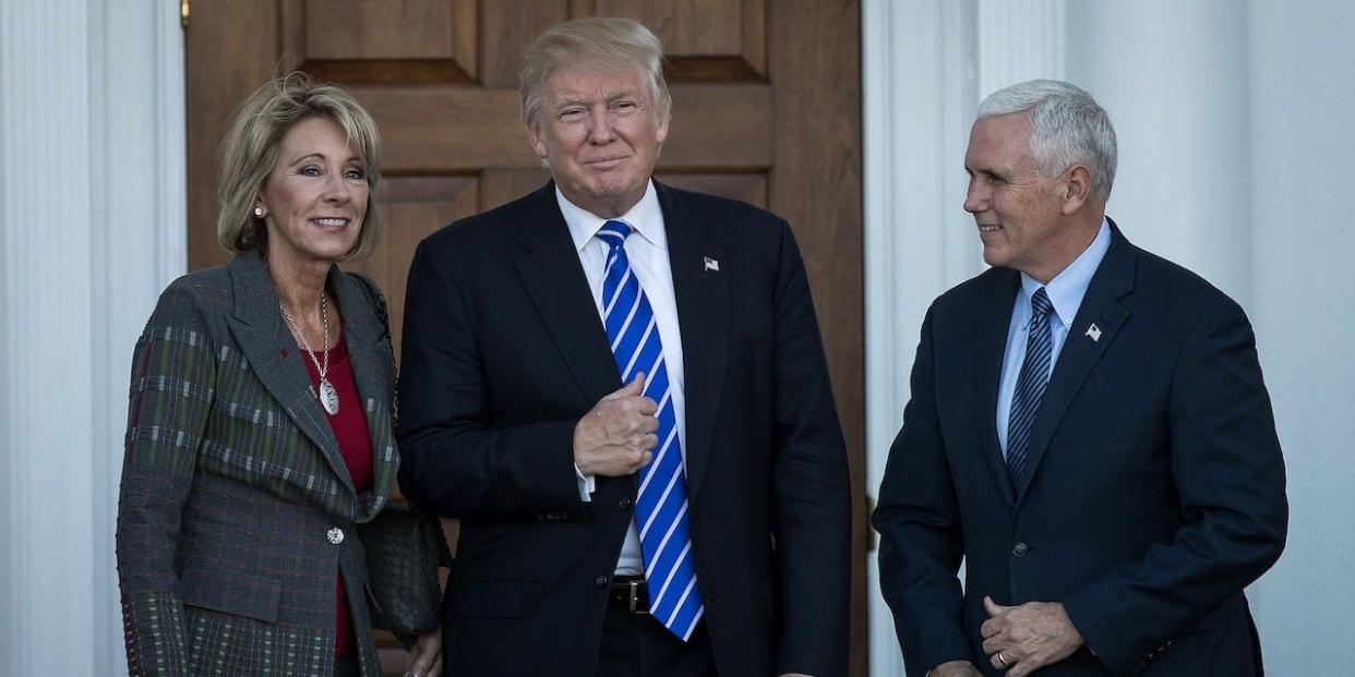 Betsy DeVos, president-elect Donald Trump and vice president-elect Mike Pence pose for a photo outside the clubhouse at Trump International Golf Club.