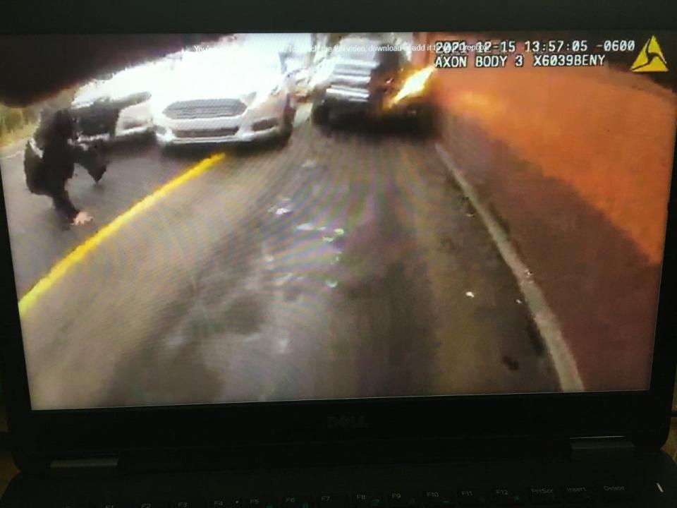 A screen shot from a body camera video shows an officer slipping and falling in front of a white vehicle. The officer whose body camera this is appears to have opened fire at this moment.