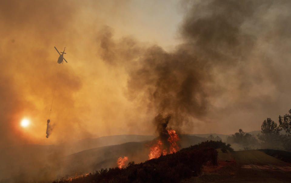 A helicopter drops water on a burning hillside during the Ranch Fire in Clearlake Oaks, Calif., Sunday, Aug. 5, 2018. (AP Photo/Josh Edelson)