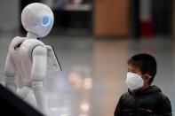 Boy wears a mask watching a robot at the Pudong International Airport in Shanghai
