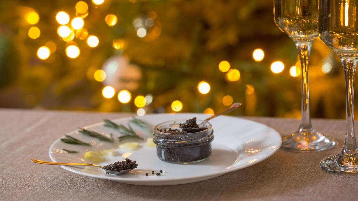 black caviar and glass of champagne on background christmas tree