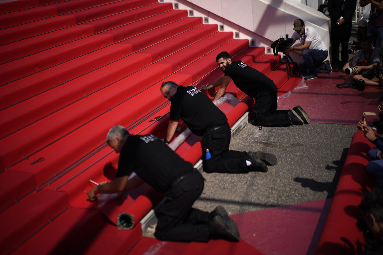 Crew members install the red carpet at the Palais des Festivals ahead of the opening day of the 75th international film festival, Cannes, southern France, Tuesday, May 17, 2022. The Cannes film festival runs from May 17 until May 28 2022. (AP Photo/Daniel Cole)