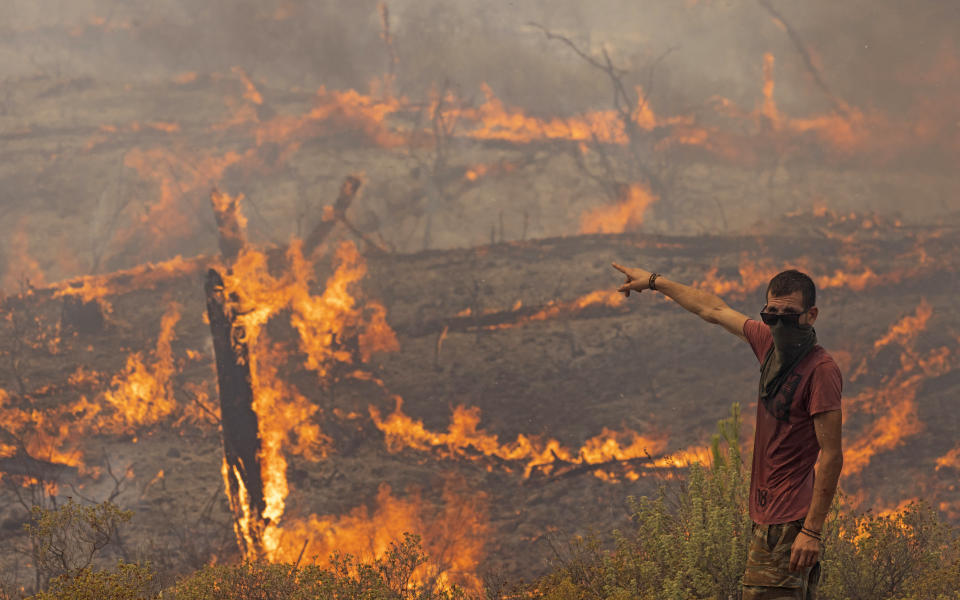 APOLLANA, GREECE - JULY 27: (EDITOR'S NOTE: Alternate crop) A man stands ready to fight flames as they engulf a hillside on July 27, 2023 in Apollana, Rhodes, Greece. Flames continue to spread on the island of Rhodes as Greece battles some 63 fires across the country during an intense heatwave. The fires on Rhodes prompted preventive evacuations of tens of thousands of tourists in the middle of the high summer season. (Photo by Dan Kitwood/Getty Images)