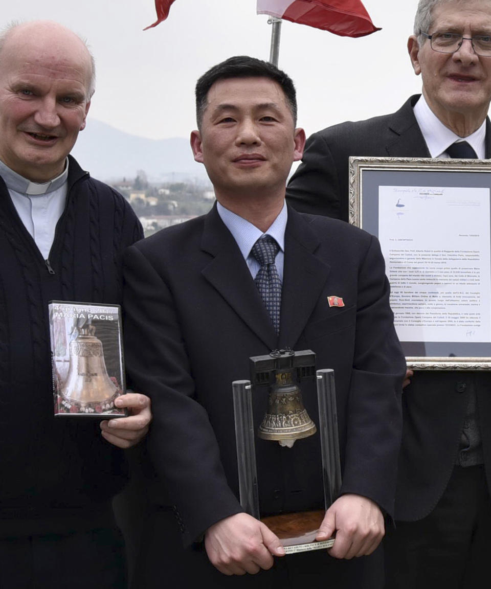 FILE - This March 20, 2018, file photo made available on Jan. 3, 2019, by the Parish of Farra di Soligo shows North Korea's acting Ambassador to Italy Jo Song Gil, center, holding a model of "Bell of Peace of Rovereto" during a cultural event on the occasion of a visit of the North Korean delegation to the Veneto region in San Pietro di Feletto, near Treviso, northern Italy. Jo, a senior North Korea diplomat who vanished in Italy in late 2018, lives in South Korea under government protection, lawmakers said Wednesday, Oct. 7, 2020. Also seen are don Brunone De Toffol, parish priest of Farra di Soligo, left, and Senator Valentino Perin, right. (Parish of Farra di Soligo via AP, File)