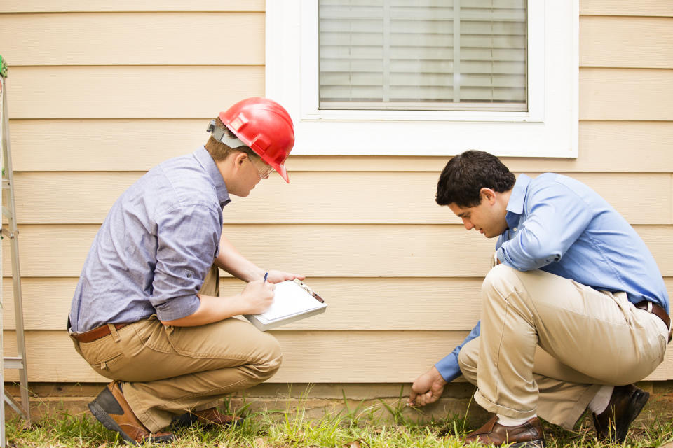 Two men looking at the foundation of a house