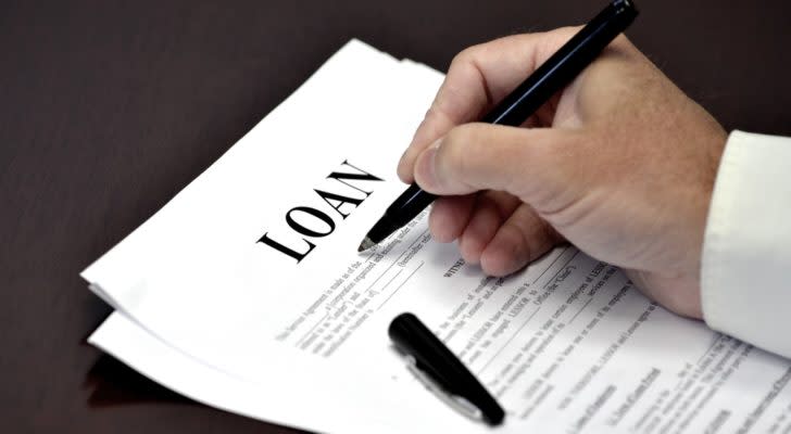 Image of a hand signing a paper with the loan as the title