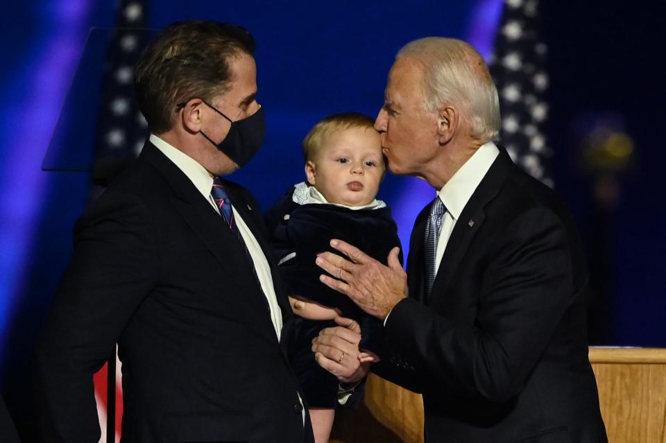 Joe Biden kisses his grandson held by Hunter Biden