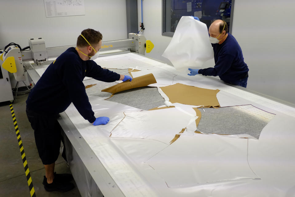 Dallara USA employees Michael Carlisle, left, and Marty Bigley cut out material patterns for protective medical gowns during the coronavirus pandemic, Wednesday, April 15, 2020, in Indianapolis. (AP Photo/Darron Cummings)