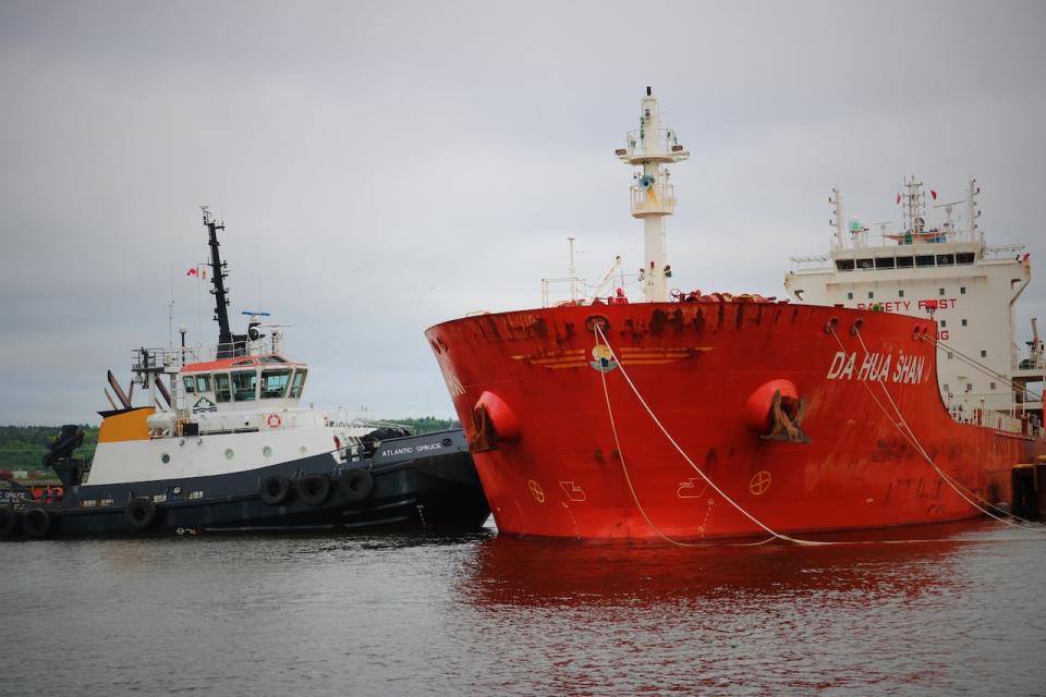 The Atlantic Spruce applies pressure to the side of a large oil tanker, allowing longshoremen to loosen the lines tethering it to the dock. 