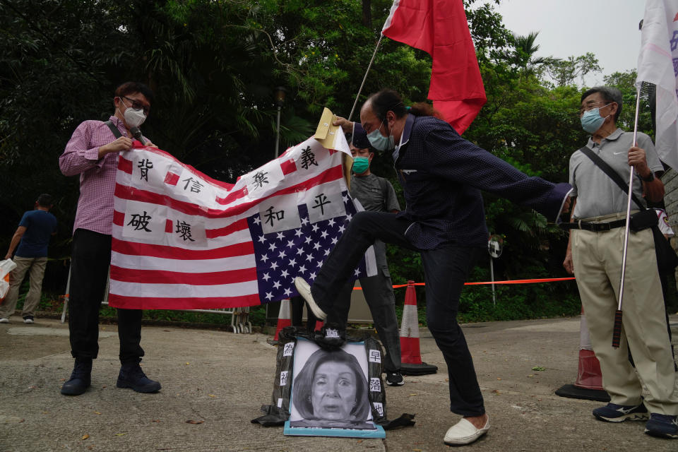 Pro-China supporters step on a picture of U.S. House Speaker Nancy Pelosi during a protest outside the Consulate General of the United States in Hong Kong, Wednesday, Aug. 3, 2022. U.S. House Speaker Nancy Pelosi arrived in Taiwan late Tuesday, becoming the highest-ranking American official in 25 years to visit the self-ruled island claimed by China, which quickly announced that it would conduct military maneuvers in retaliation for her presence. (AP Photo/Kin Cheung)