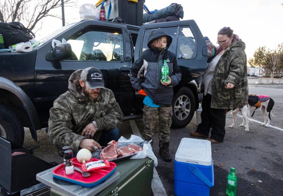 Thomas Lowder cooks dinner on a camping stove while Aiden, 10, drinks a soda and Bonnie pulls out food crumbs from the inside of the car. The Lowders often get by on frozen meals they microwave at gas stations, but they like to cook fresh food after Bonnie’s paydays.