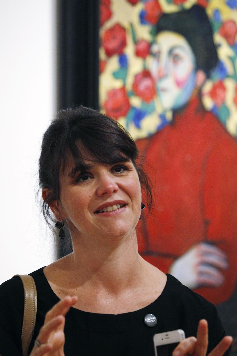 In this photo taken Tuesday, Oct. 9, 2012, Cecile Debray, curator of modern collections at the Pompidou Center, talks in front of an oil painting by Sonia Delaunay (Philomena, 1907) as part of one of two new exhibits featuring art exclusively by women at the Seattle Art Museum, in Seattle. Included in the exhibition is the only U.S. stop for an exhibit from the Pompidou Center in Paris, home of the modern art museum there, of painting, sculpture, drawing, photography and video. The exhibit runs through Jan. 13, 2013. (AP Photo/Elaine Thompson)