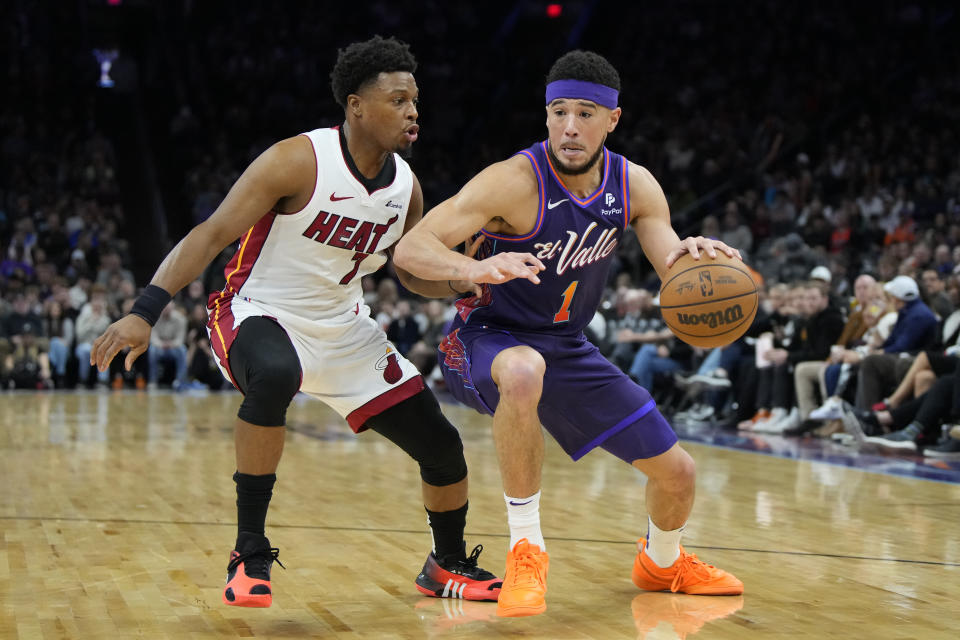 Phoenix Suns guard Devin Booker, right, drives against Miami Heat guard Kyle Lowry, left, during the first half of an NBA basketball game, Friday, Jan. 5, 2024, in Phoenix. (AP Photo/Rick Scuteri)