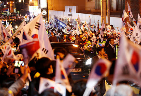 A vehicle carrying South Korea's ousted leader Park Geun-hye drives past her supporters as she arrives at her private home in Seoul, South Korea, March 12, 2017. REUTERS/Kim Kyung-Hoon