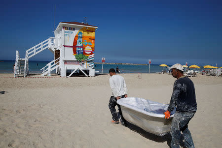 Workers carry a bath tub as they renovate a lifeguard tower into a luxury hotel suite, as part of an international online competition, at Frishman Beach in Tel Aviv, Israel March 8, 2017. Picture taken March 8, 2017. REUTERS/Baz Ratner