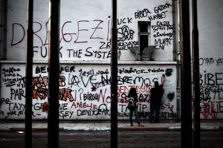 A demonstrator writes slogans on a building painted with graffiti at Taksim Square in Istanbul on June 6, 2013