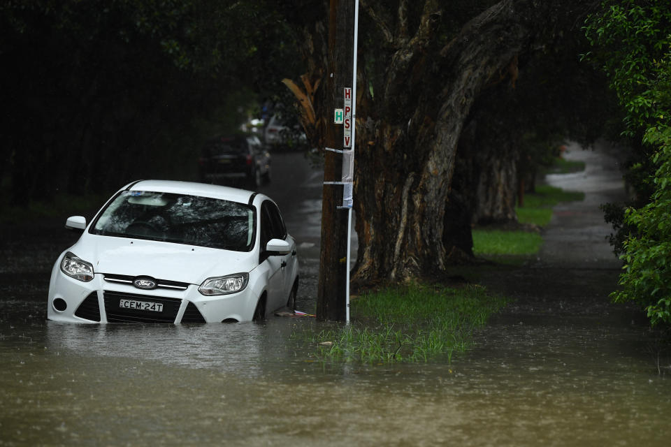 Pictured is a white car being submerged by floodwater at Marrickville.