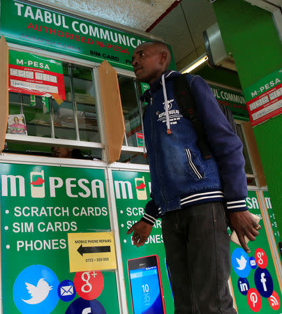 A customer prepares to conduct a mobile money transfer, known as M-Pesa, at a Safaricom agent stall in downtown Nairobi, Kenya October 16, 2018. REUTERS/Thomas Mukoya