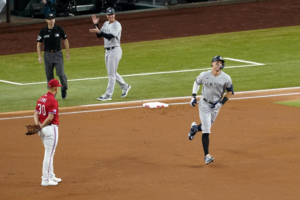 New York Yankees' Aaron Judge rounds the bases past Texas Rangers first baseman Nathaniel Lowe (30), umpire Lew Williams and first base coach Travis Chapman after hitting hit a solo home run, his 62nd of the season, in the first inning of the second baseball game of a doubleheader in Arlington, Texas, Tuesday, Oct. 4, 2022. With the home run, Judge set the AL record for home runs in a season, passing Roger Maris. (AP Photo/Tony Gutierrez)