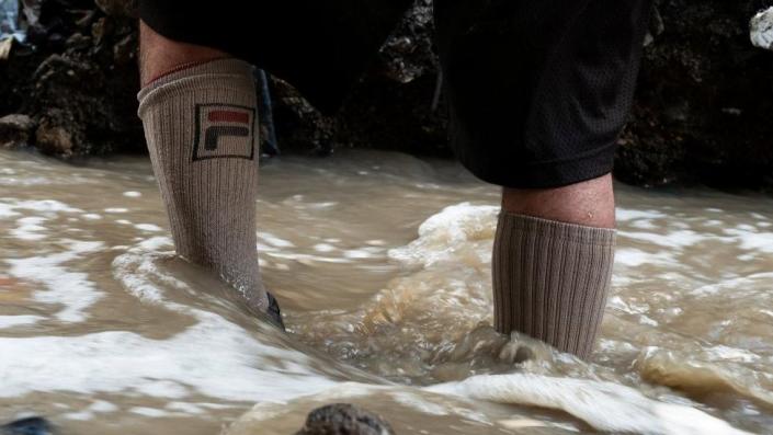 Un hombre busca chatarra en las aguas contaminadas del río Las Vacas