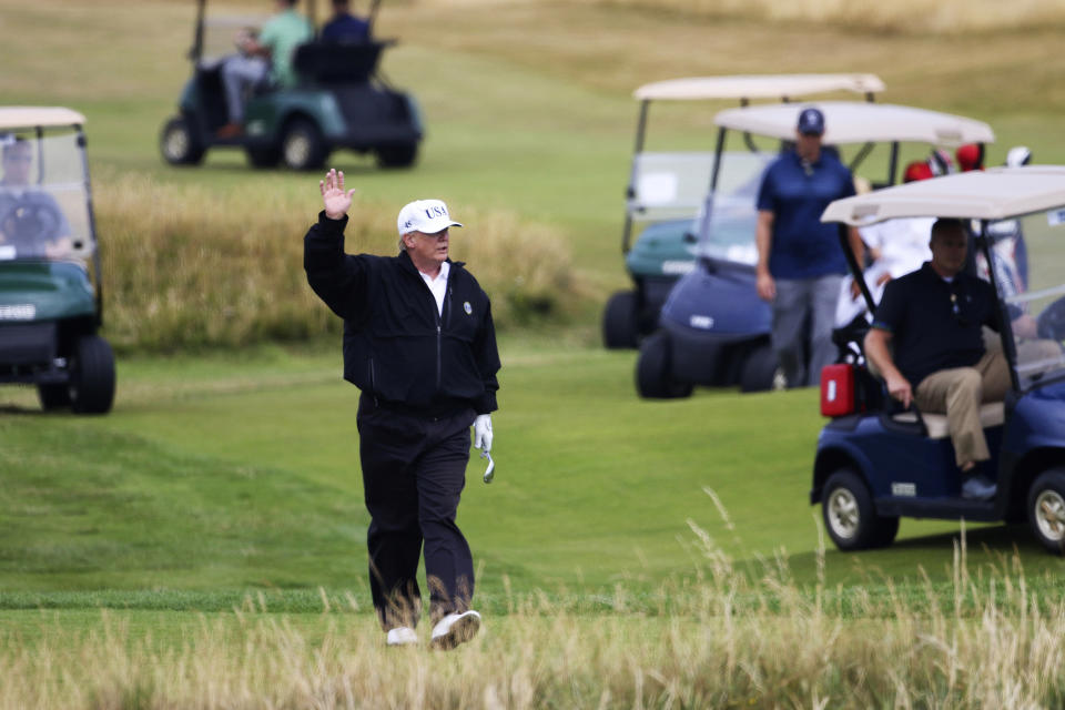 FILE - President Donald Trump waves to protesters while playing golf at Turnberry golf club, in Turnberry, Scotland, July 14, 2018. A New York judge ruled Friday, Feb. 16, 2024, against Trump, imposing a $364 million penalty over what the judge ruled was a yearslong scheme to dupe banks and others with financial statements that inflated the former president's wealth. (AP Photo/Peter Morrison, File)