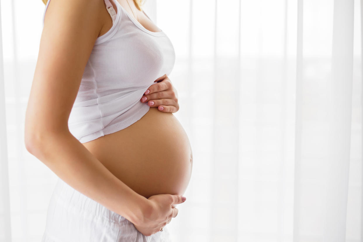 Pregnant woman standing next to window 