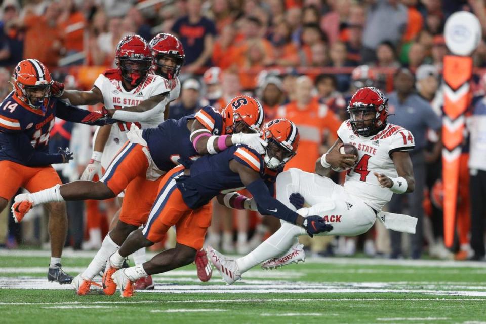 Syracuse defensive back Garrett Williams (8) and linebacker Mikel Jones (3) tackle North Carolina State quarterback Jack Chambers (14) during the first half of an NCAA college football game Saturday, Oct. 15, 2022, in Syracuse, N.Y.