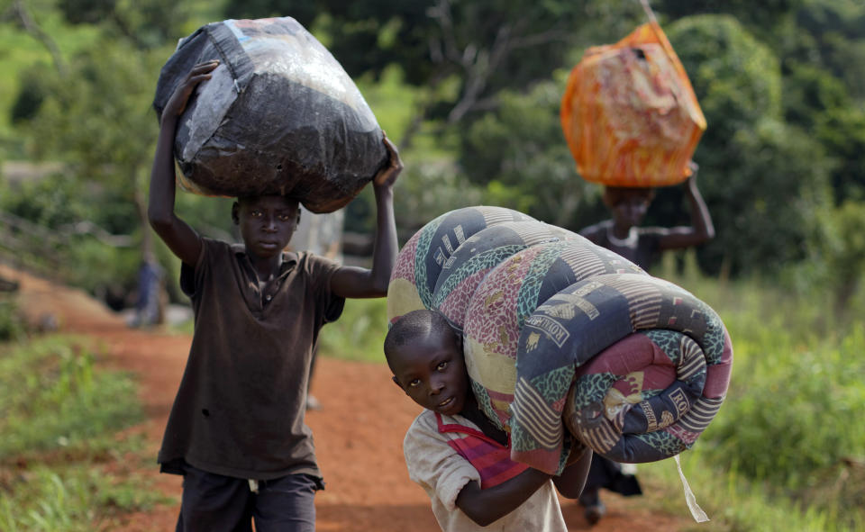 FILE - In this Thursday, June 8, 2017 file photo, South Sudanese refugees Peter Lemi, 14, left, brother Thomas Wani, 12, and mother Rose Sunday, walk up a hill after crossing a wooden bridge from South Sudan to Uganda at the Busia crossing, near Kuluba, in northern Uganda. The representative of the United Nations refugee agency in Uganda says "major gaps" in funding are constraining their work in the East African country sheltering 1.3 million refugees. Joel Boutroue told reporters in the Ugandan capital, Kampala, on Thursday, Sept. 12, 2019 that UNHCR in Uganda is operating at only 35% of the total requirements.(AP Photo/Ben Curtis, File)