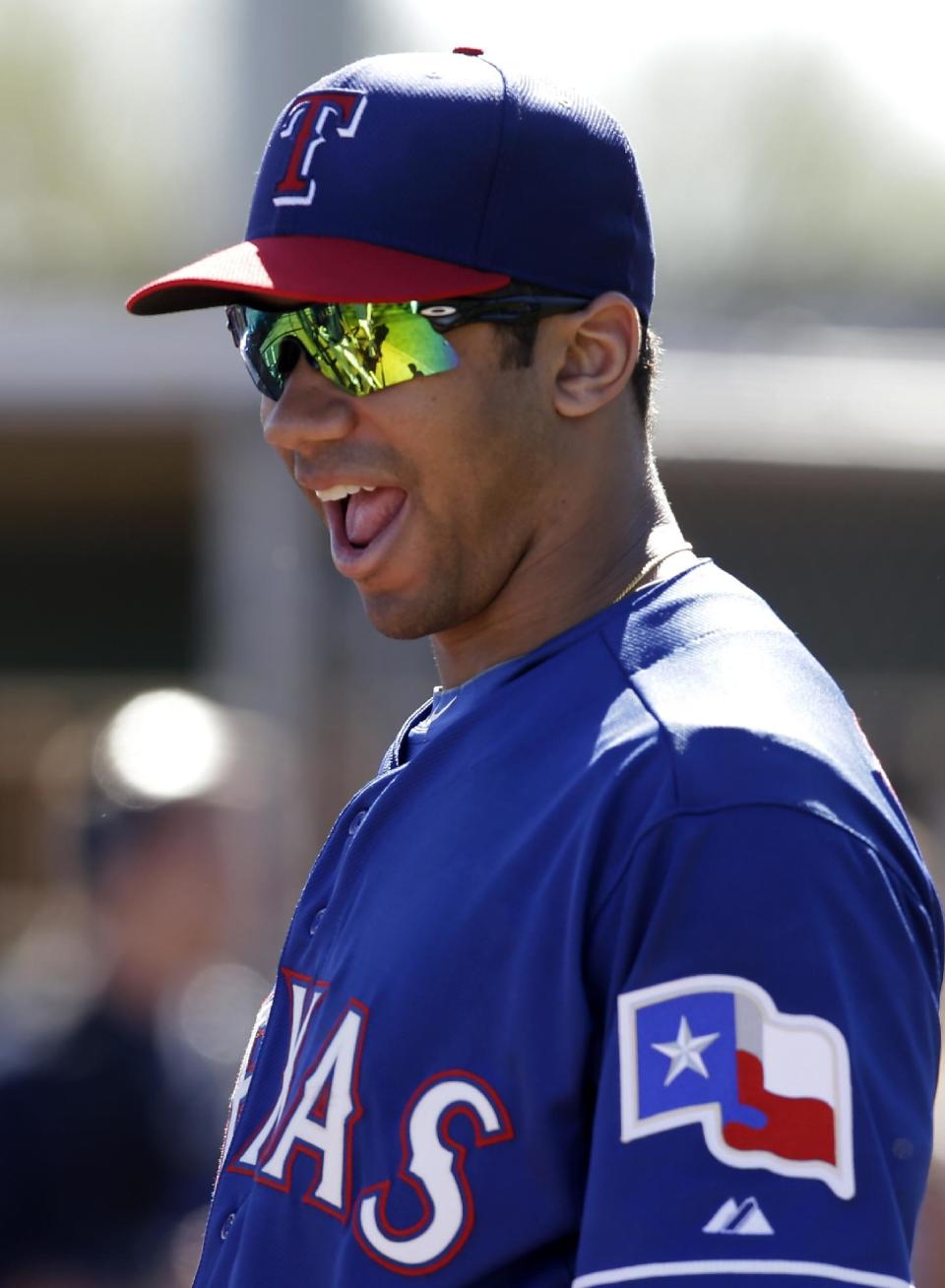 Seattle Seahawks quarterback Russell Wilson laughs as he watches Texas Rangers players take batting practice during spring training baseball, Monday, March 3, 2014, in Surprise, Ariz. (AP Photo/Tony Gutierrez)