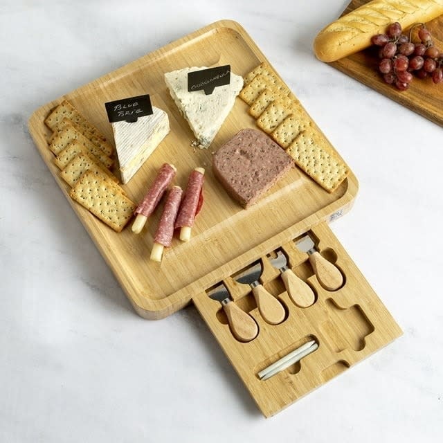 bamboo charcuterie board with crackers, meat, cheese, and utensils