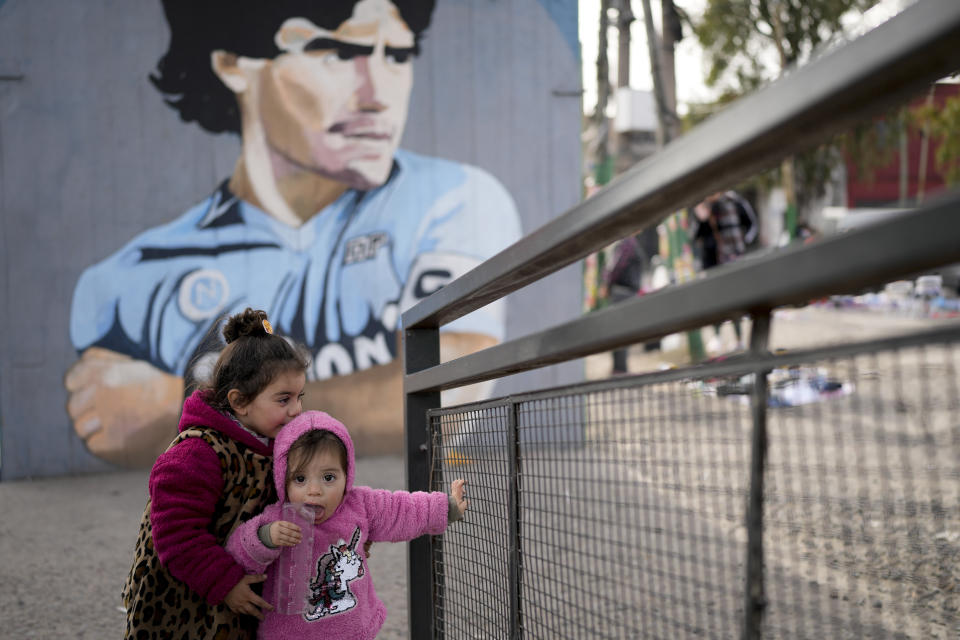 Niños juegan cerca de un mercado donde la gente puede comprar o intercambiar productos en las afueras de Buenos Aires, Argentina, el miércoles 10 de agosto de 2022. (AP Foto/ Natacha Pisarenko)