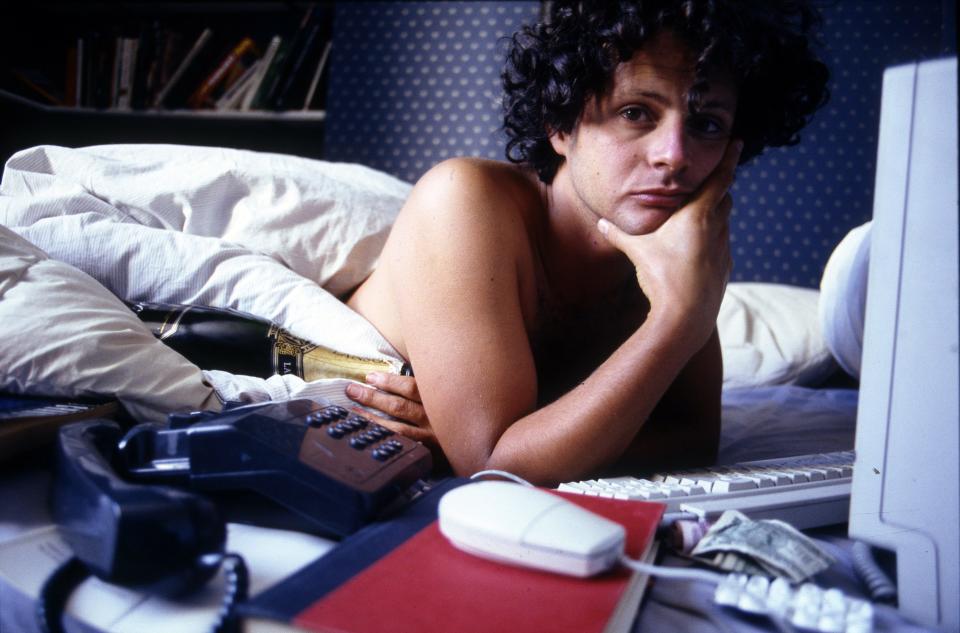 Journalist and editor James Brown lies in bed with an Apple Macintosh computer, a bottle of champagne and a phone, London, United Kingdom, 1997. Brown co-founded the magazine Loaded in 1994. (Photo by Martyn Goodacre/Getty Images)