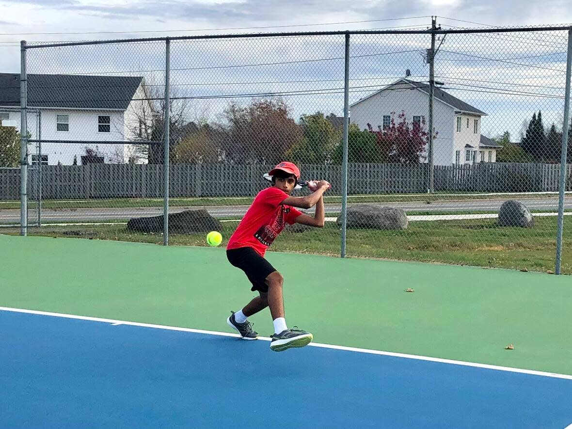 Nehan Javed takes advantage of the summer-like temperature to spend some extra time on the tennis court in Fredericton. (Jennifer Sweet/CBC - image credit)