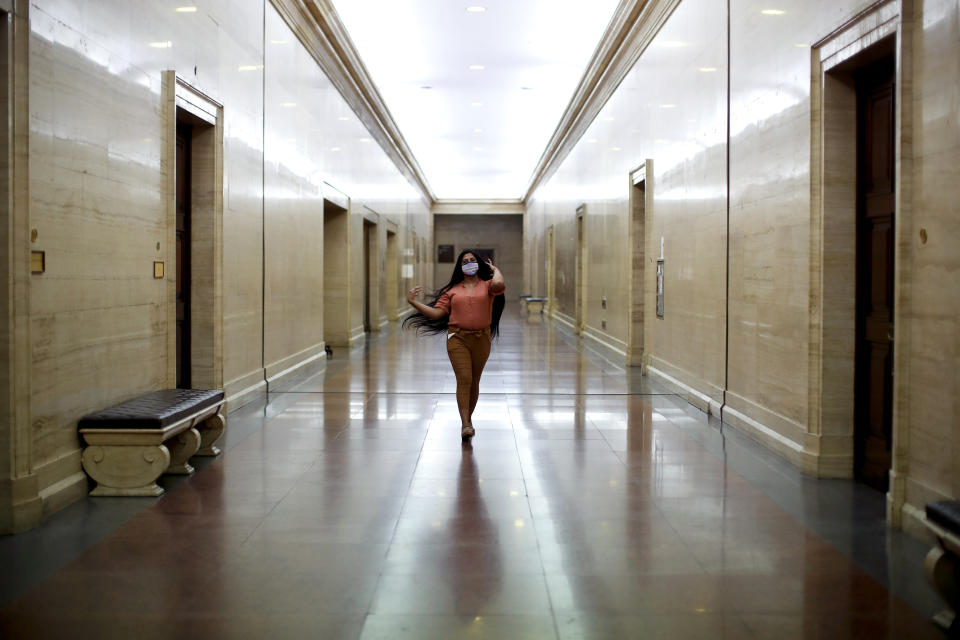 Transgender woman Angeles Rojas poses for a photo as she walks down a corridor of the National Bank where she works in Buenos Aires, Argentina, Thursday, Nov. 5, 2020. The 23-year-old joined the human resources department of Banco Nación, Argentina's leading state bank, this year, after President Alberto Fernández signed a decree establishing a 1% employment quota for transgender people in the public sector. (AP Photo/Natacha Pisarenko)