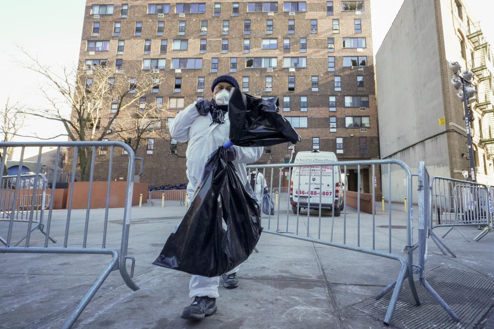 Workers in protective clothing remove debris from the building which suffered the city's deadliest fire in three decades, in the Bronx borough of New York, Tuesday, Jan. 11, 2022. A malfunctioning electric space heater apparently started the fire Sunday in the 19-story building in the Bronx, fire officials said. (AP Photo/Mary Altaffer)