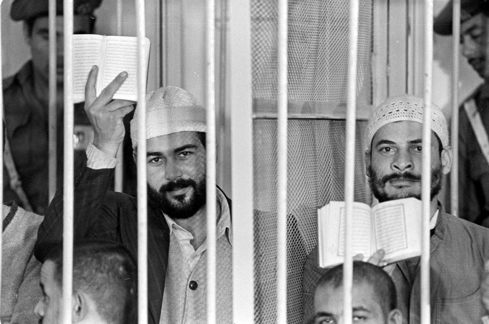 FILE - In this Nov. 30, 1981 file photograph, Khalid al-Islambouli, left, and Abdel Hamid Abdel Aal hold up open Qurans during the second day of their trial in Cairo, Egypt, Monday, Nov. 30, 1981. The two were among 24 Muslim fundamentalists put on trial for conspiring in the assassination of President of Egypt Anwar Sadat. Iran's 1979 Islamic Revolution initially inspired both Islamic militants and Islamists across the Mideast. They saw the revolution as the starting gun in a competition to push out the strongman Arab nationalism that had taken hold across the Middle East. However, analysts say Iran's push to back militants in the wider Mideast and Saudi Arabia's efforts to mobilize the Sunni world against the Shiite power would turn many away. (AP Photo, File)