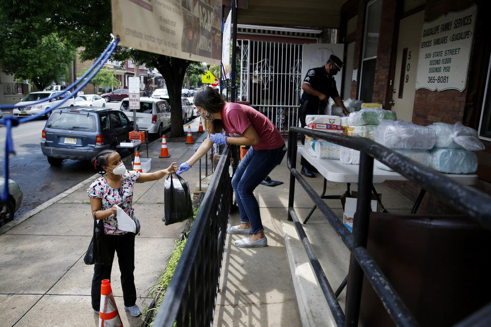 In this June 11, 2020, photo Lourdes Sherby, center, with Guadalupe Family Services, hands diapers to Louisa Peralta in Camden, N.J. “I think we’re received a lot better than we used to be,” said Sgt. Dekel Levy, 41, as he helped hand out diapers to a steady stream of young mothers Thursday afternoon at Guadalupe Family Service. (AP Photo/Matt Slocum)