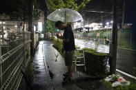 A couple prays after placing flowers near the Kyoto Animation building, Friday, July 18, 2019, in Kyoto, Japan. A man screaming "You die!" burst into an animation studio in Kyoto, doused it with a flammable liquid and set it on fire Thursday, killing several people in an attack that shocked the country and brought an outpouring of grief from anime fans. (AP Photo/Jae C. Hong)