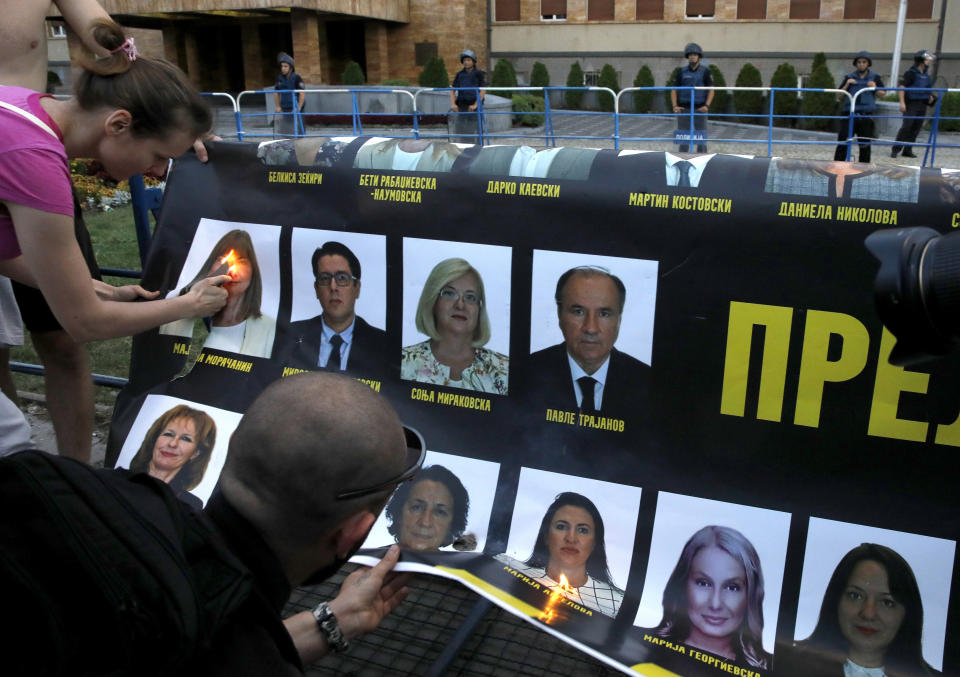 Protesters burn a poster with portraits of the ruling coalition lawmakers during a protest in front of the parliament building in Skopje, North Macedonia, on Wednesday, July 6, 2022. Thousands of people were marching the fifth night of protests in North Macedonia's capital after French President Emmanuel Macron last week announced the proposal, which many in the small Balkan country find controversial. (AP Photo/Boris Grdanoski)