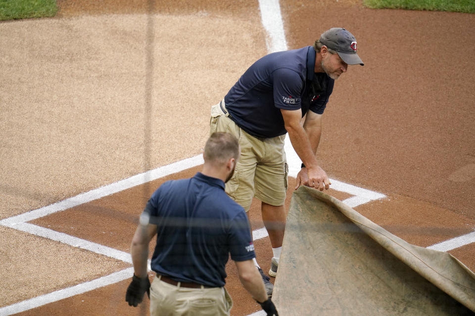 Grounds crew workers cover the plate as the Minnesota Twins baseball game against the Cleveland Indians was postponed, Saturday, June 26, 2021, in Minneapolis, due to heavy rain forecast in the area for much of the day. (AP Photo/Jim Mone)