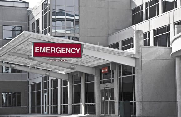 The outside of a hospital showing an overhang with an Emergency sign.