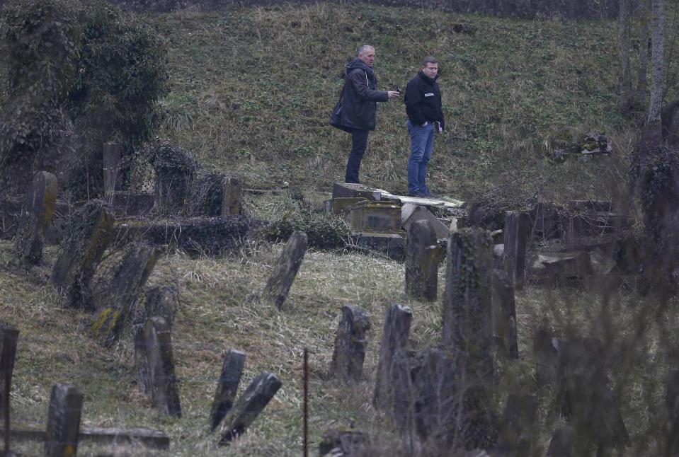 French investigators are seen near a desecrated tombstone at the Sarre-Union Jewish cemetery, eastern France