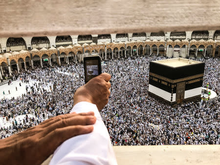 A muslim pilgrim takes a video with his mobile phone while others circle the Kaaba and pray at the Grand mosque ahead of annual Haj pilgrimage in the holy city of Mecca, Saudi Arabia August 16, 2018.REUTERS/Zohra Bensemra