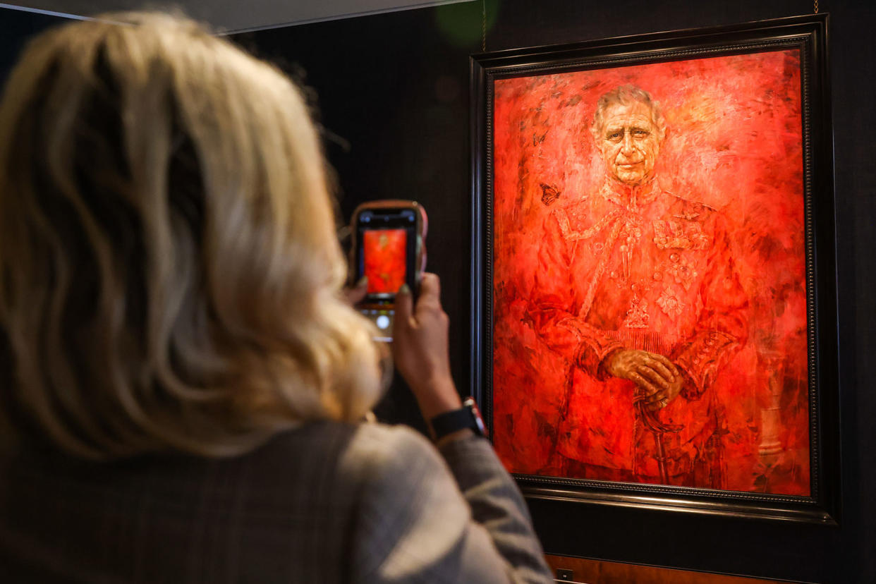 woman takes photographs of King Charles III portrait Stringer/Anadolu via Getty Images
