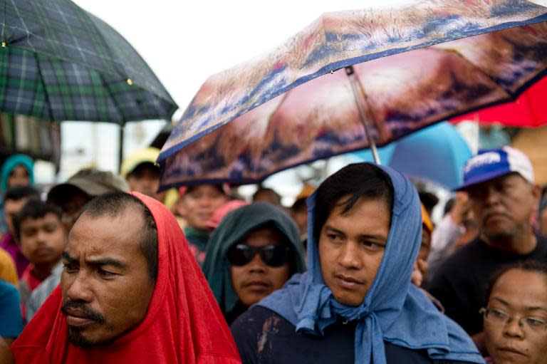 Victims of Super Typhoon Haiyan queue for food aid to be distributed in Tacloban on November 23, 2013