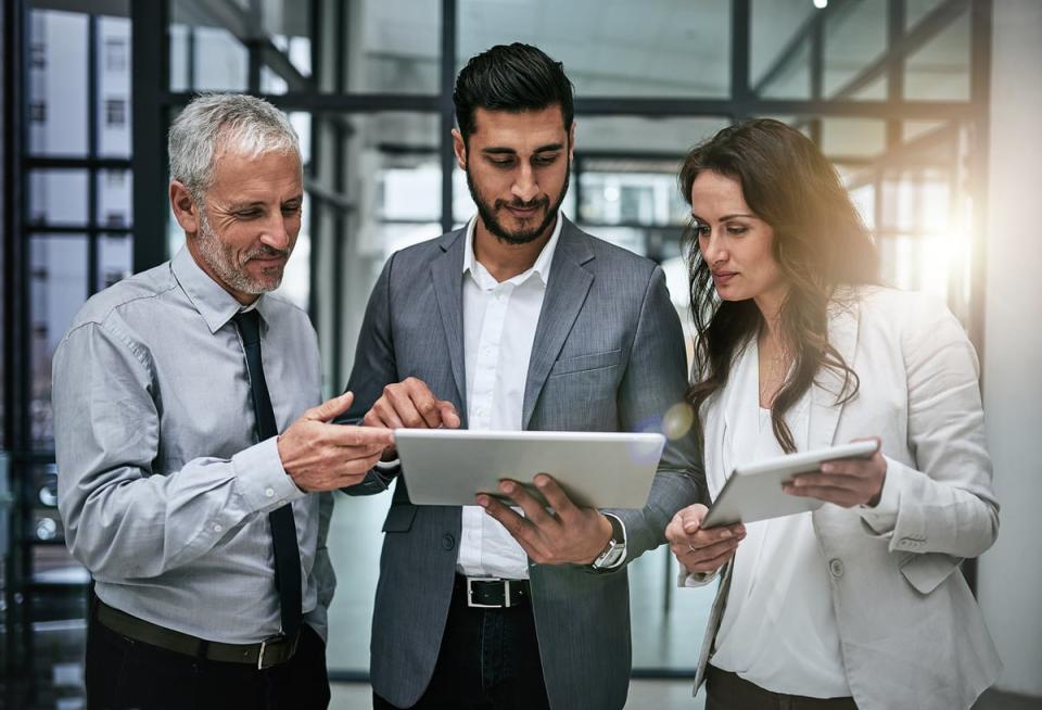 Three business people looking at a tablet.