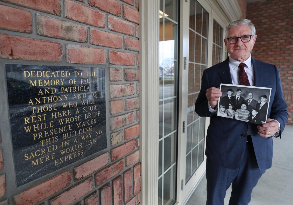 Funeral director David Anthony holds a family portrait from 1973 while standing next to a plaque memorializing his parents at the Kucko-Anthony-Kertesz Funeral Home on South Main Street in Akron. His parents were murdered 50 years ago.