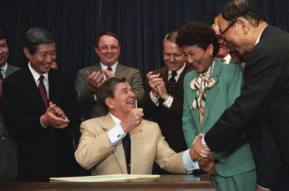 FILE - President Ronald Reagan celebrates with senators and representatives during a signing ceremony in the Old Executive Office Building in Washington on Aug. 10, 1988. Reagan signed into law legislation making moral and financial amends to Japanese-Americans kept in U.S. internment camps during World War II. From left are Sen. Spark Matsunaga, D-Hawaii; Rep. Patricia Saiki, R-Hawaii; Sen. Pete Wilson, R-Calif.; Rep. Don Young, R-Alaska; and Rep. Robert Matsui, D-Calif. Japanese Americans in their 70s and 80s inspired by the civil rights movement and who pushed for redress in the 1980s are among the most outspoken advocates of reparations for Black Americans. (AP Photo/Doug Mills, File)